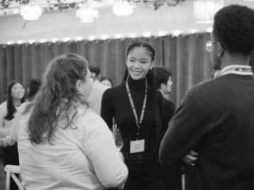 Two UM students talking to a UM Alum at a dinner gathering.